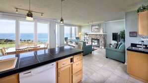 A kitchen with a view of the ocean, a dining area with chairs, a sofa, and a fireplace. - Paradise Regained Condo, Whale Watching & Pool (Depoe Bay)