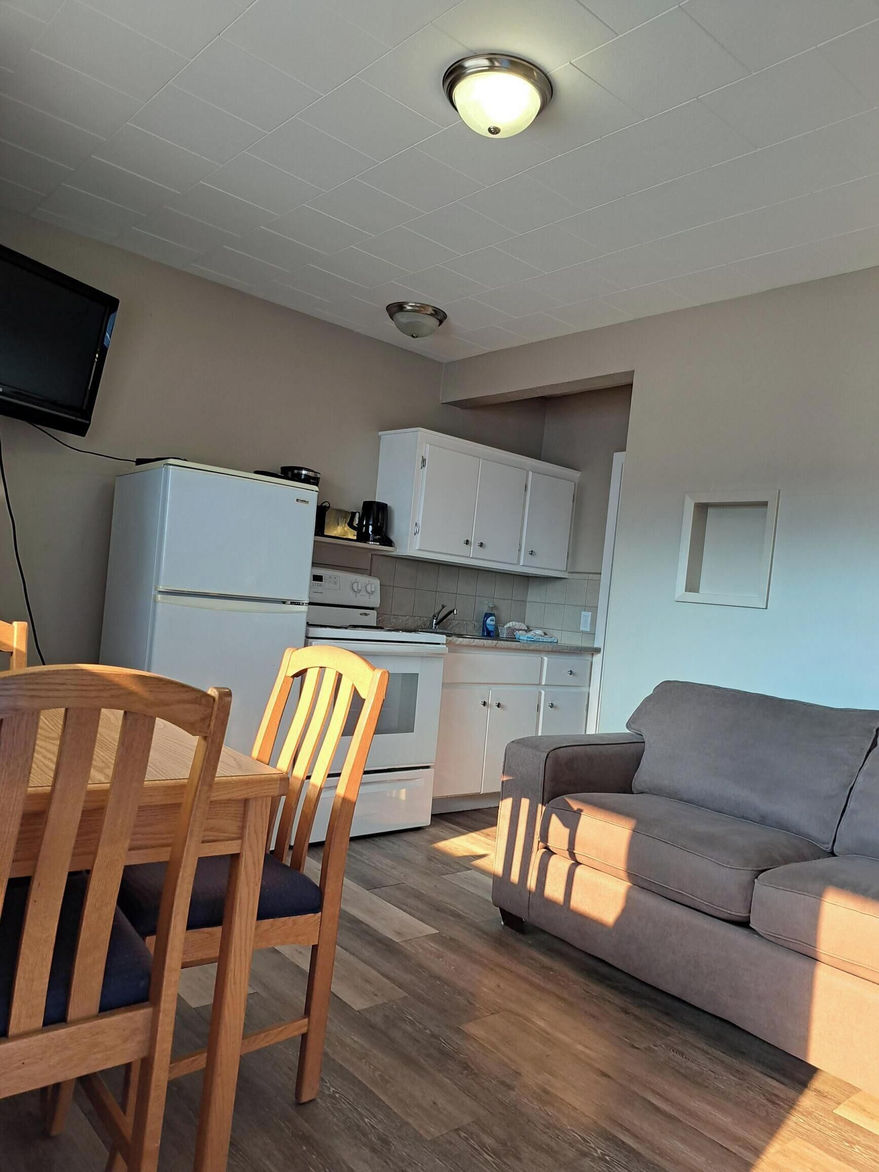 A compact living space with a kitchenette, a dining area with a table and chairs, and a sofa.