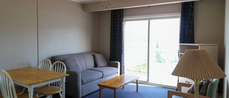 A room with a ceiling fan, a sofa, a wooden table, and a lamp.
