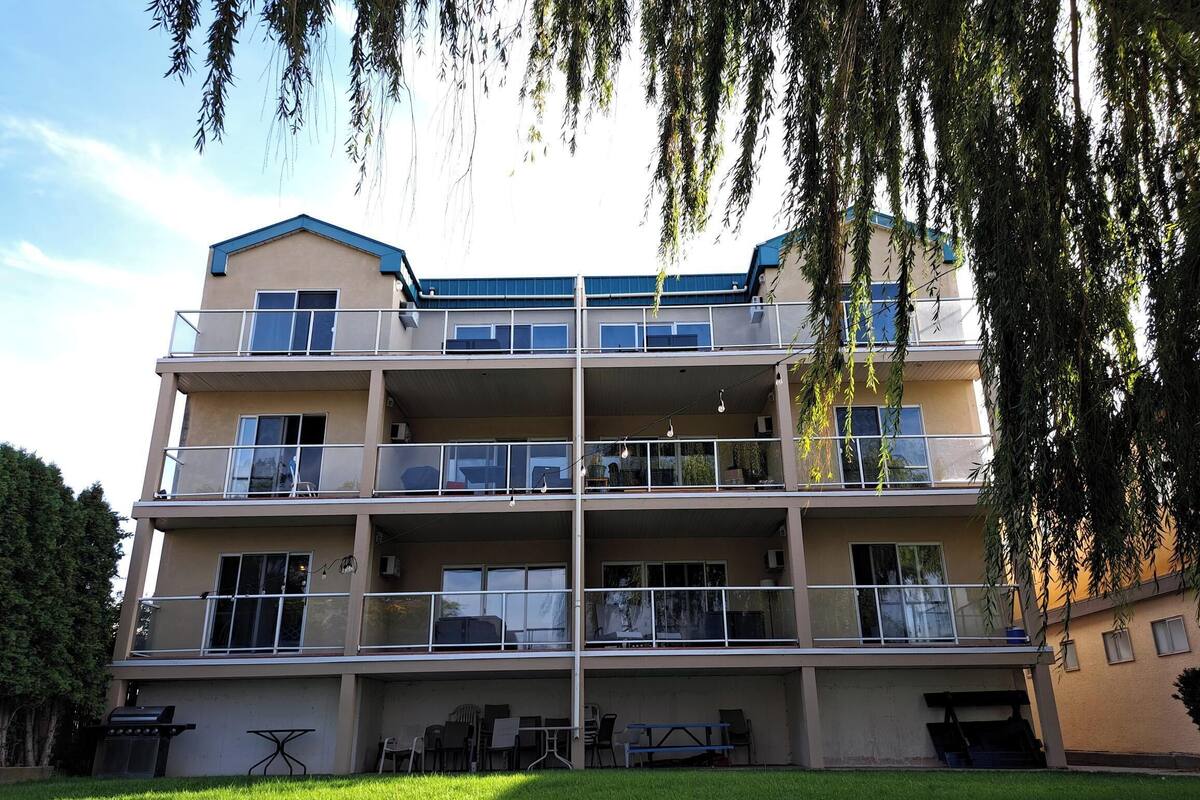 A multi-story residential building with balconies, a barbecue area, and a grassy courtyard.