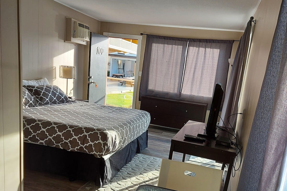 A compact hotel room with a bed, a small table, and a chair.
