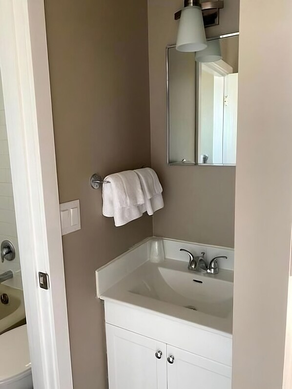 A bathroom with a white sink, a mirror, and a towel hanging on a rack.