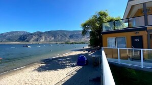 Een hotel aan het strand met een helder uitzicht op zee en bergen op de achtergrond.
