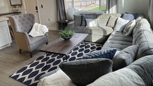 Ein Wohnzimmer mit grauem Sofa, Couchtisch und einem gemusterten Teppich.