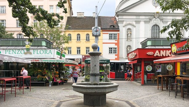 A cobblestone plaza with a central fountain, surrounded by cafes and shops. - Modern Landstraße 1BR w/ Amazing Views, steps from Danube, by Blueground (Vienna)