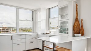 Una cocina moderna con armarios blancos, encimera blanca y un ventanal con vistas a la ciudad.