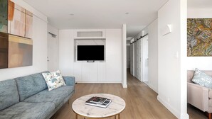 Una sala de estar moderna con un sofá, una mesa de centro y un televisor montado en la pared.
