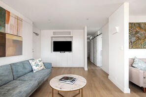 Un salon moderne avec un canapé, une table basse et un téléviseur fixé au mur.