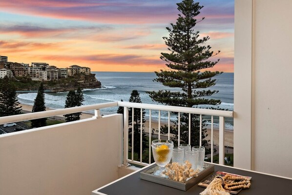 Un balcon avec vue sur l’océan et sur le coucher du soleil.