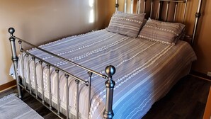 Une chambre à coucher avec un lit en métal, une couvre-lit à rayures et un tapis à motifs.