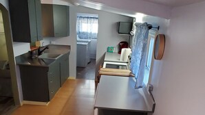 Une cuisine de taille réduite comprenant un évier, des placards et un coin repas avec une table et des chaises.