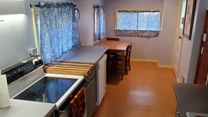 Une cuisine de taille réduite équipée d’une cuisinière, d’un four et d’une table à manger avec des chaises.