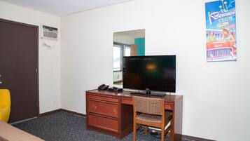 Una habitación de hotel con escritorio, silla, televisión y un cartel en la pared.