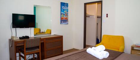Habitación de hotel con cama, escritorio, silla, televisor y puerta que da a un baño.