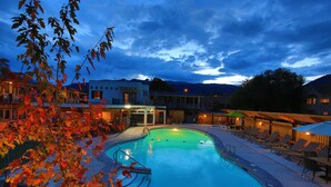 A swimming pool with lounge chairs and a building in the background. - Bowmont Motel (Penticton)