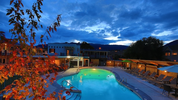 Una piscina con sillas de descanso y un edificio al fondo.