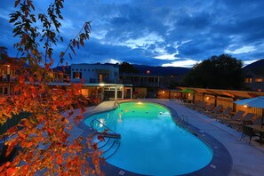 A swimming pool with lounge chairs and a building in the background. - Bowmont Motel (Penticton)