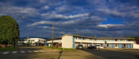 A motel with a two-story structure, a pedestrian crossing, and a parking lot with cars.