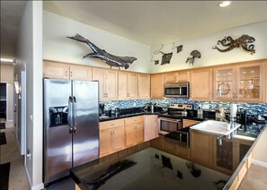 A modern kitchen with wooden cabinets, stainless steel appliances, and decorative wall art.