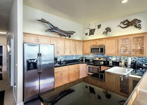 A modern kitchen with wooden cabinets, stainless steel appliances, and decorative wall art.