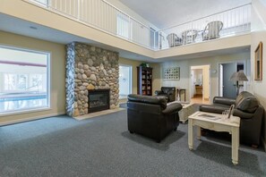 A spacious living room with a stone fireplace, leather sofas, a coffee table, and a balcony with outdoor seating. - Captains Cove, Balcony, Sweeping Views & Pool (Depoe Bay)