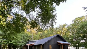 Eine Hütte mit großer Veranda, umgeben von Bäumen und einem See.