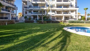 A modern multi-story apartment building with a swimming pool and well-maintained lawn. - Nice apartment for 4 people with A/C, WIFI, pool, TV and terrace (Denia)