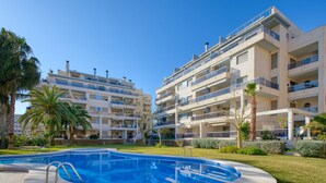 A modern apartment building with a swimming pool and palm trees. - Nice apartment for 4 people with A/C, WIFI, pool, TV and terrace (Denia)
