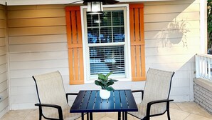 A covered patio area with a ceiling fan, two chairs, a table, and a window with shutters. - 3BR/4BA w/ Great place for having fun in the middle of the city!!!! (Atlanta)