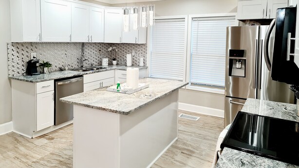 A modern kitchen with white cabinetry, a granite countertop, a stainless steel refrigerator, and a built-in oven. - 3BR/4BA w/ Great place for having fun in the middle of the city!!!! (Atlanta)