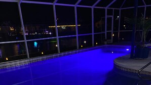 An indoor swimming pool with blue lighting, a view of the night sky, and a patio area with a railing. - Punta Gorda Isles Jewel with 45ft dock,just4minutes from Fishville and downtown. (Punta Gorda)