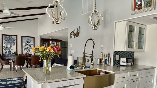 A modern kitchen with a central island, white cabinetry, gold handles, and a stainless steel sink. - Punta Gorda Isles Jewel with 45ft dock,just4minutes from Fishville and downtown. (Punta Gorda)