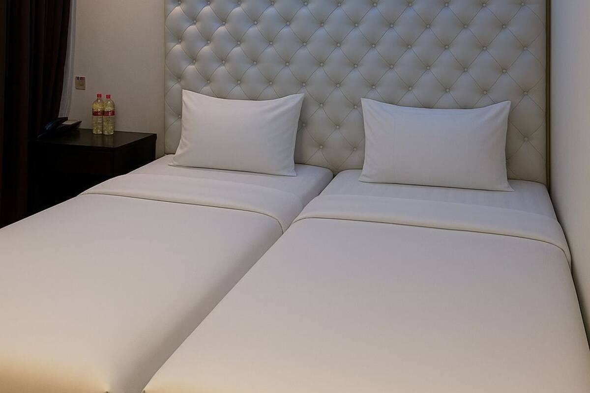 A hotel room with a large bed, a headboard, and a ceiling light.