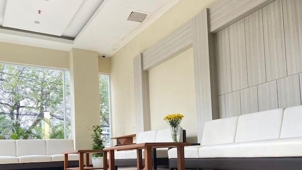 Un moderno hall de hotel con un sofá blanco, una mesa de madera y una planta en maceta.
