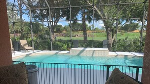 Un espace piscine avec vue sur un terrain de golf, entouré d’une structure en verre.