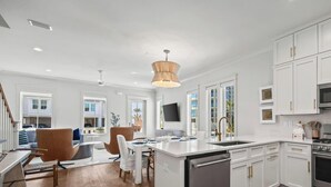 A modern kitchen with white cabinets, stainless steel appliances, and a wooden floor. - Beach Side Home, Steps from the Sand. Ocean Edge, 01 | Happy Place by Kaiser Vacation Rentals (Orange Beach)