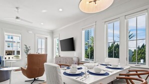 A modern dining area with a white table set for four, surrounded by wooden chairs. - Beach Side Home, Steps from the Sand. Ocean Edge, 01 | Happy Place by Kaiser Vacation Rentals (Orange Beach)