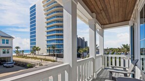 A beachfront property with a balcony, a view of the beach, and a modern building with blue-tinted windows. - Beach Side Home, Steps from the Sand. Ocean Edge, 01 | Happy Place by Kaiser Vacation Rentals (Orange Beach)