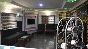A room with a TV, seating area, and a wine rack. - Captivating 1-bed Apartment in Awoyaya (Lekki)