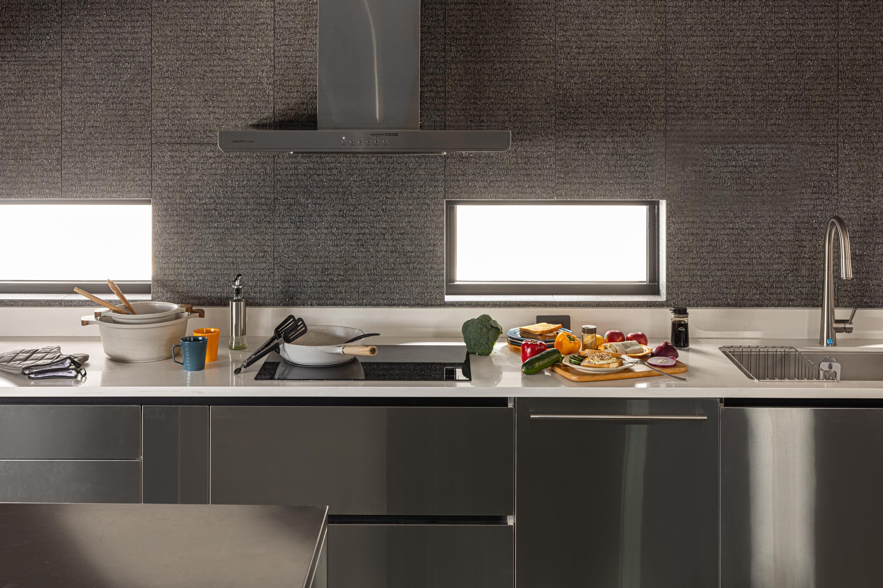 Una cocina moderna con electrodomésticos de acero inoxidable, un lavamanos doble y un amplio ventanal que proporciona luz natural.