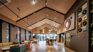 A spacious lobby with a high ceiling, wooden paneling, and a variety of seating options. - The Moment Hotel Hualien by Lakeshore (Xincheng)