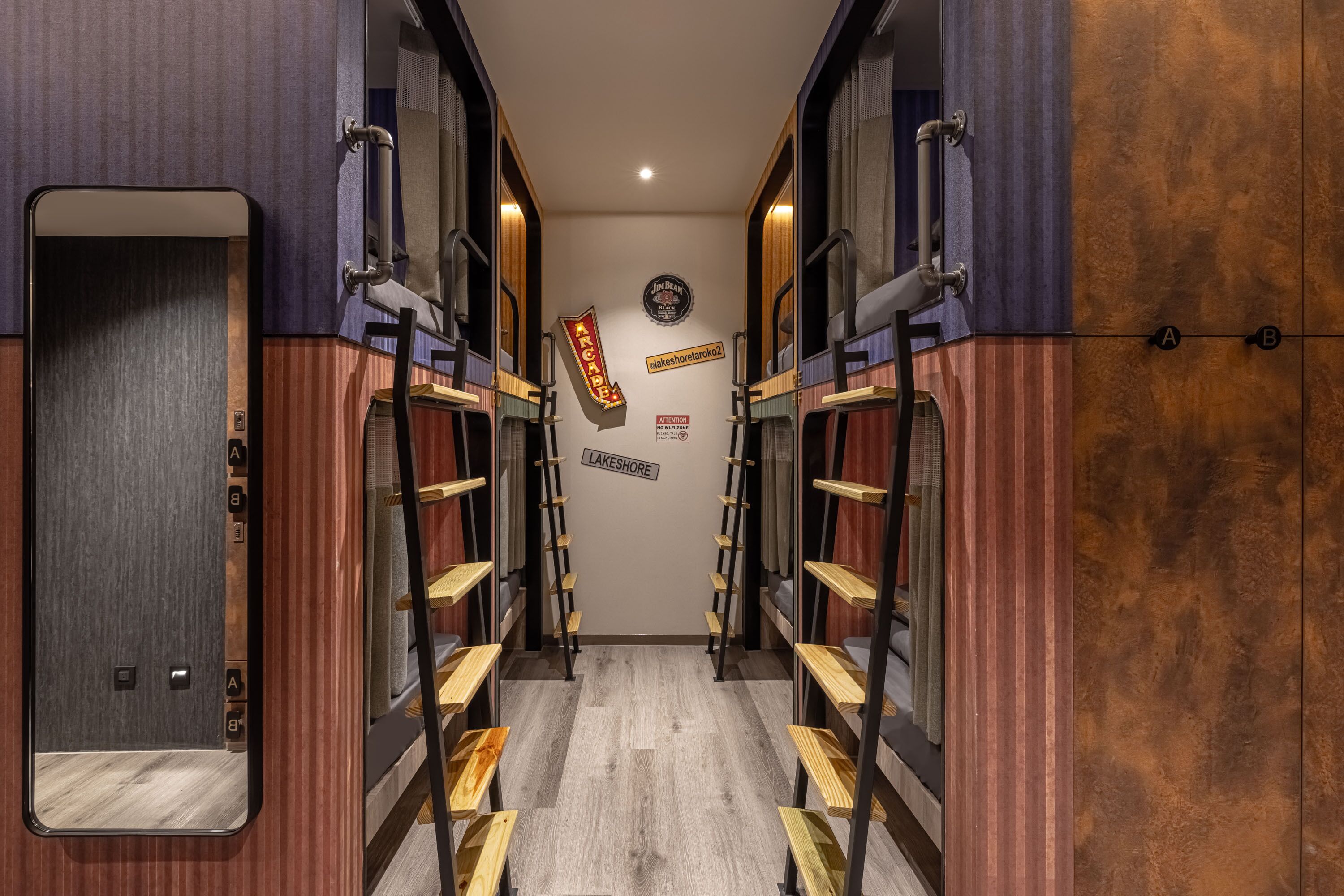 A narrow hallway with bunk beds on either side, a mirror on the left, and a sign on the wall.