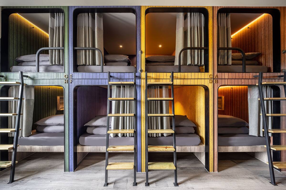 Quarto com beliche de vários níveis, escadas embutidas e prateleiras para guardar coisas.