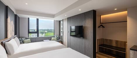 Una habitación de hotel moderna con dos camas, un ventanal grande con vistas a la ciudad, un televisor de pantalla plana montado en la pared y un banco de madera.