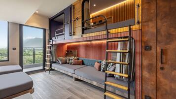 A modern loft-style room with a bunk bed, a sofa, and a balcony with a mountain view.