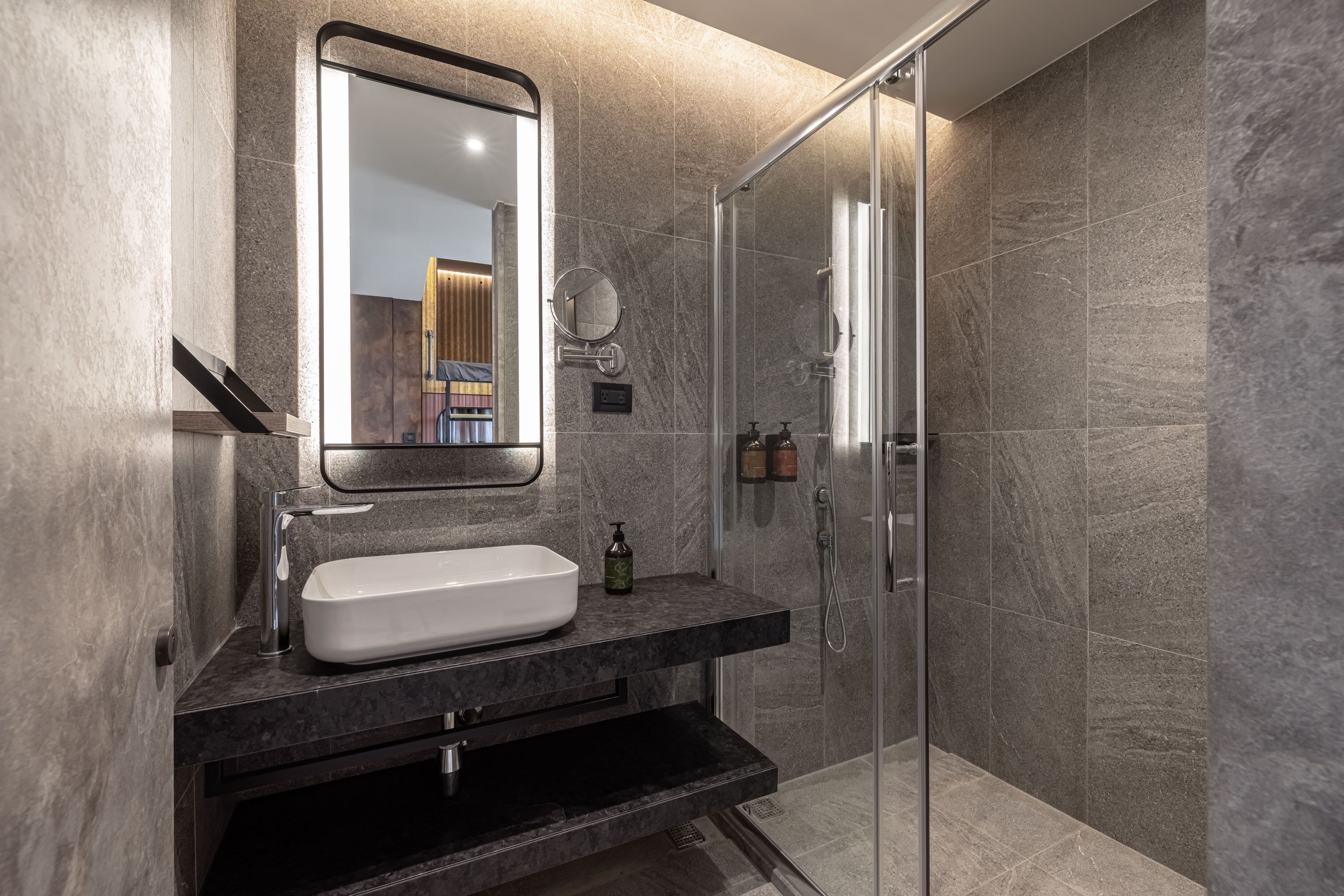 A modern bathroom with a large mirror, a white sink, and a glass-enclosed shower.