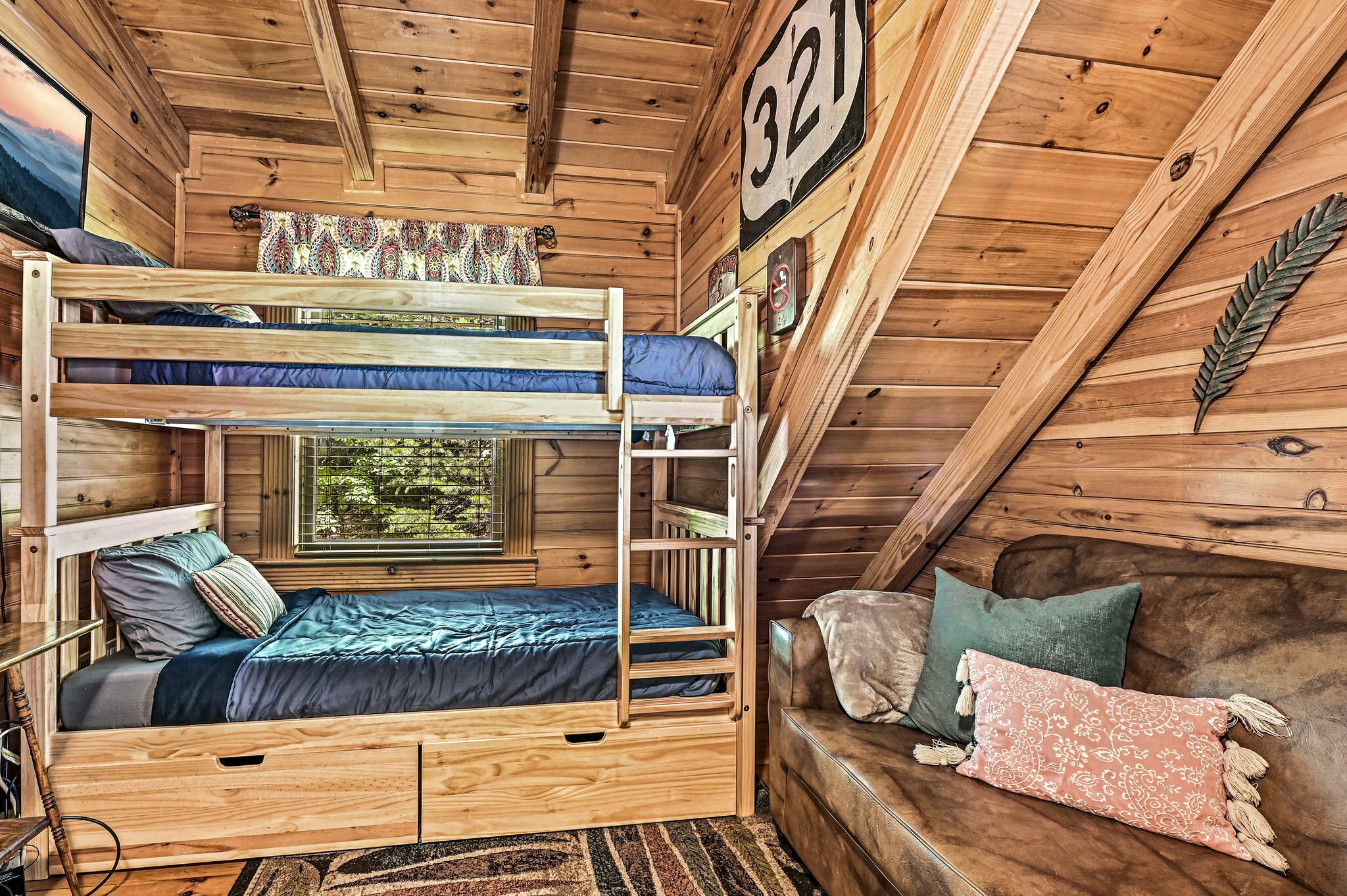 A cabin with a bunk bed, a couch, and a window with a view of trees.