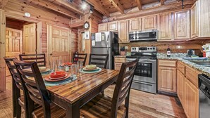 Eine Holzhütte-ähnliche Küche mit Esstisch, Stühlen, Kühlschrank, Herd und Holzschränken.