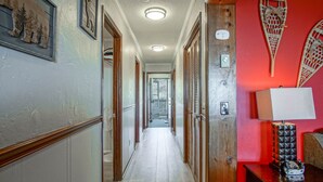 A hallway with wooden doors, a red accent wall, and a lamp on a table. - Summit 304B  3 Bedrooms 2 Full Baths (Snowshoe)