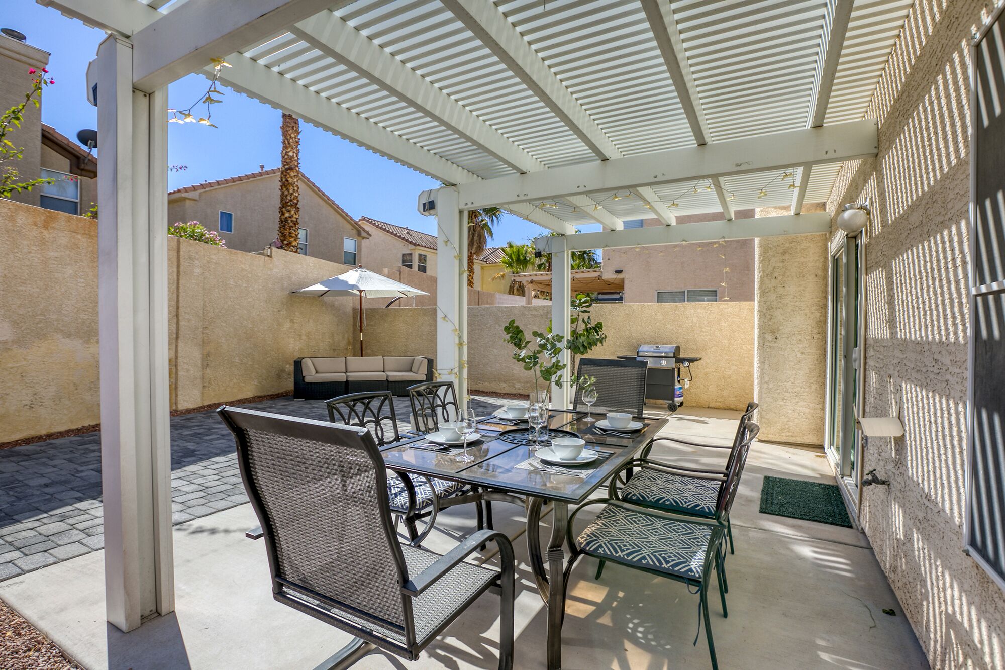 Un patio couvert comprenant une table à manger, des chaises et un barbecue.